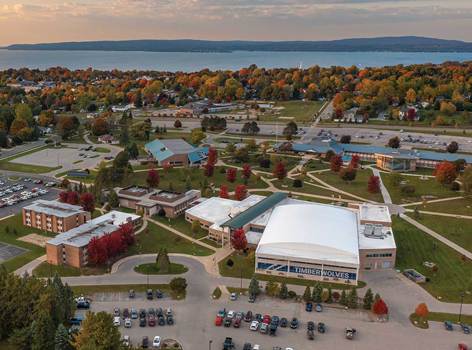 Aerial view of North Central Michigan College's Petoskey campus in autumn, with red and orange trees surrounding campus buildings and walkways